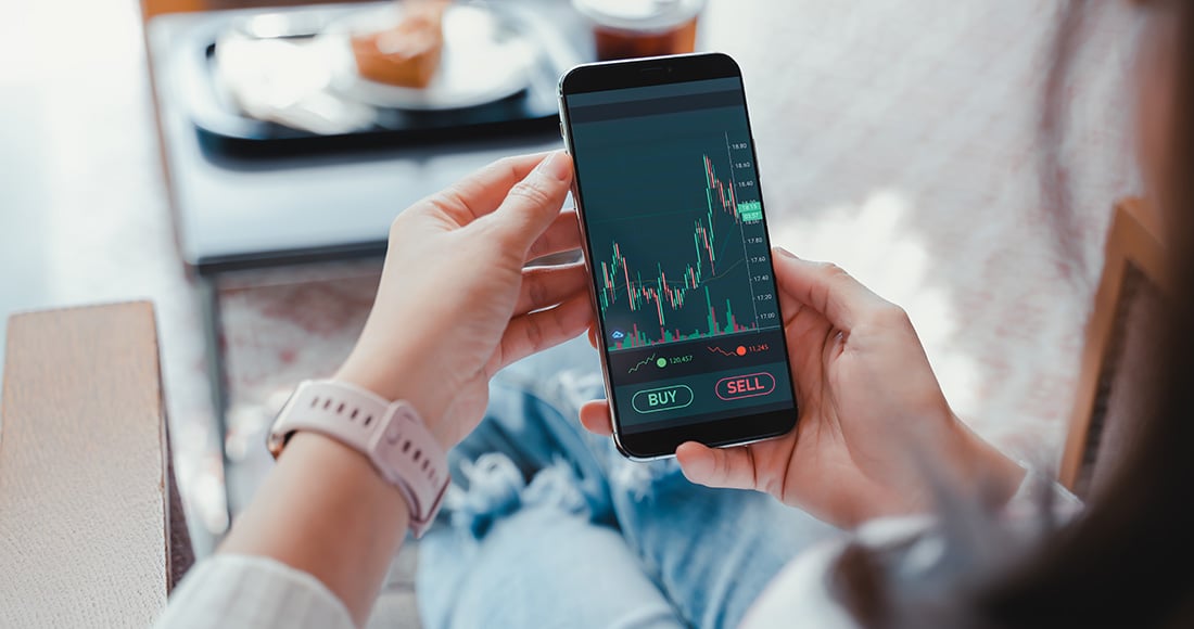 Woman holding a phone looking at stock market app
