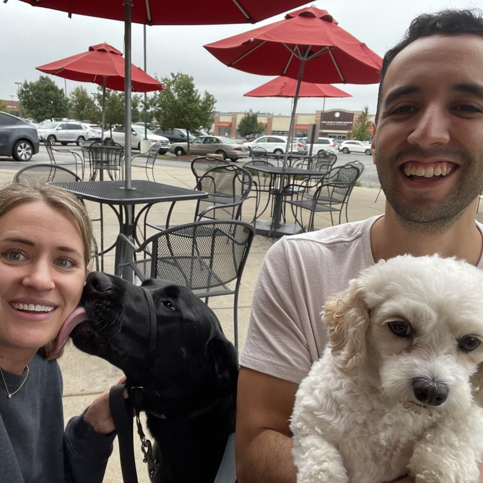 Two people with their dogs sitting outside