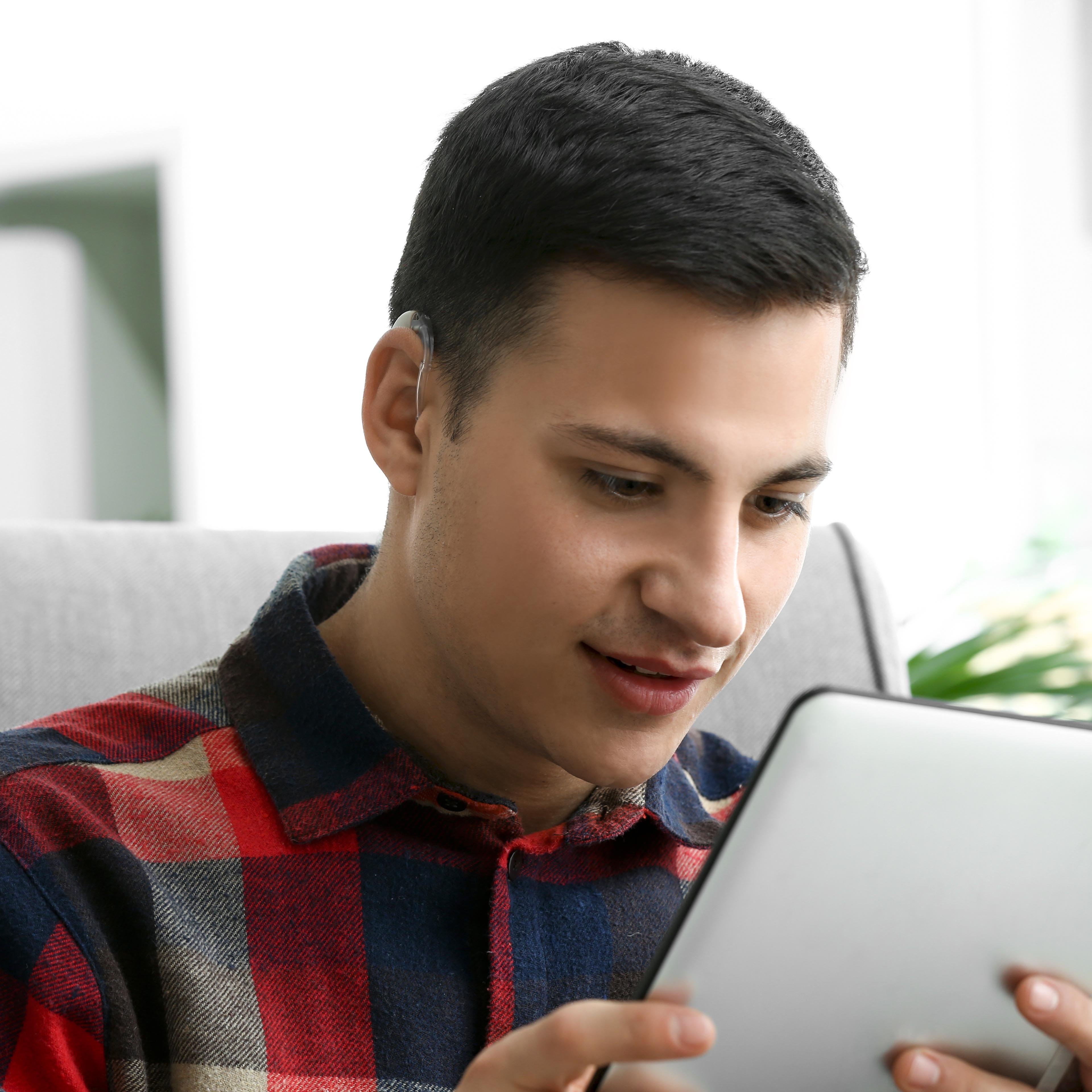 Close up of a man with an assistive hearing device looking at a tablet