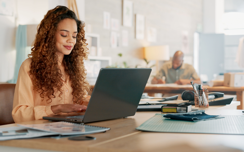 Woman working on a laptop with a peaceful smile on her face