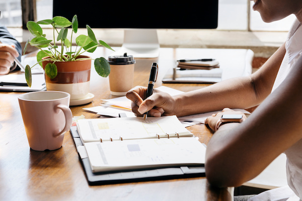 person sitting at desk writing in planner