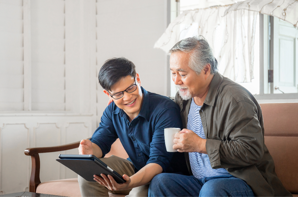 Older father and son looking at a tablet together, smiling