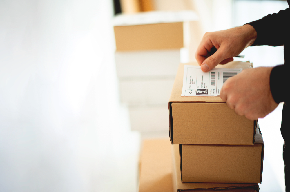 Person placing shipping label on stack of boxes