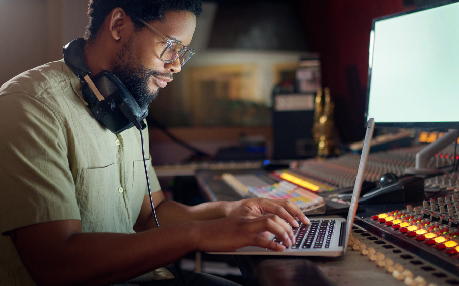 Musician typing on a laptop in a recording studio