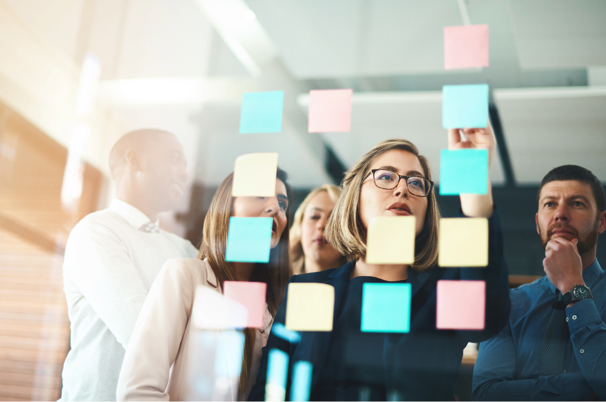 Team laying out post it notes on a glass wall