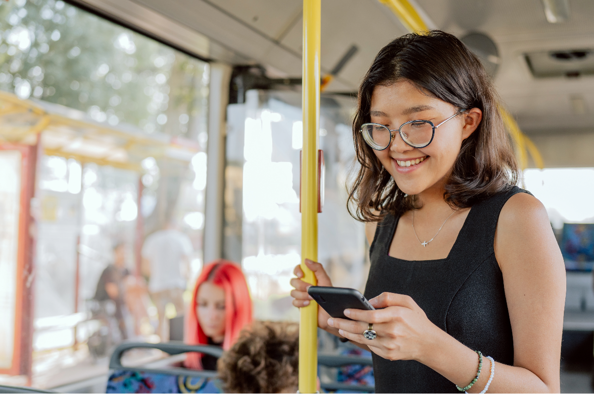young woman looking at phone on bus
