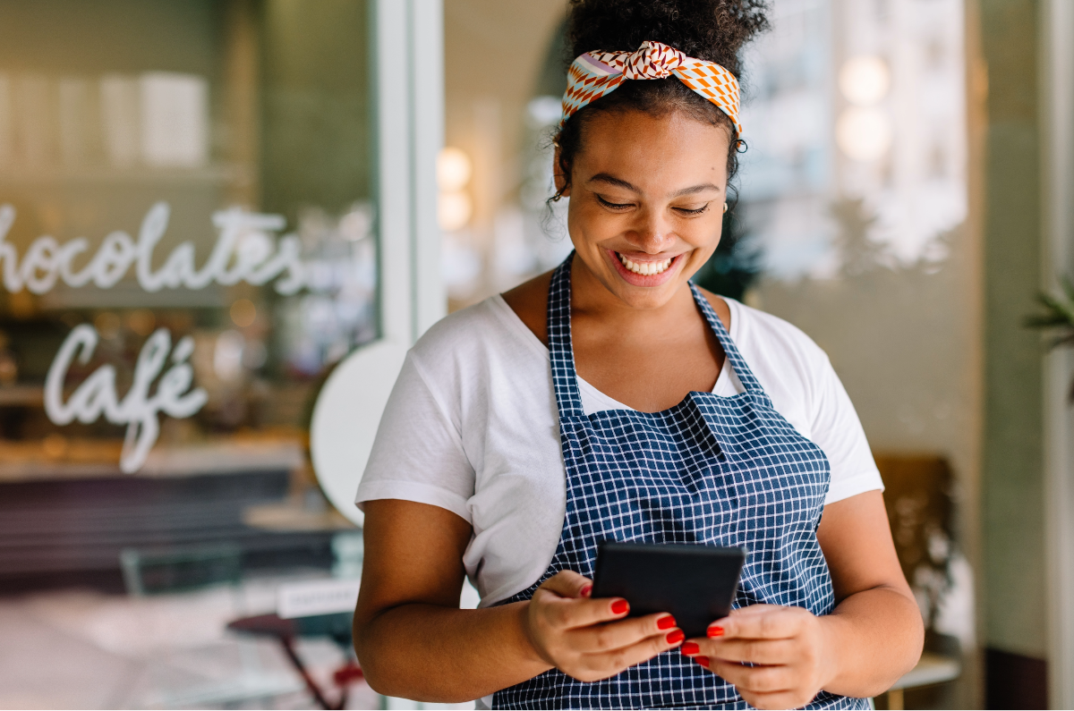 woman holding device in front of cafe