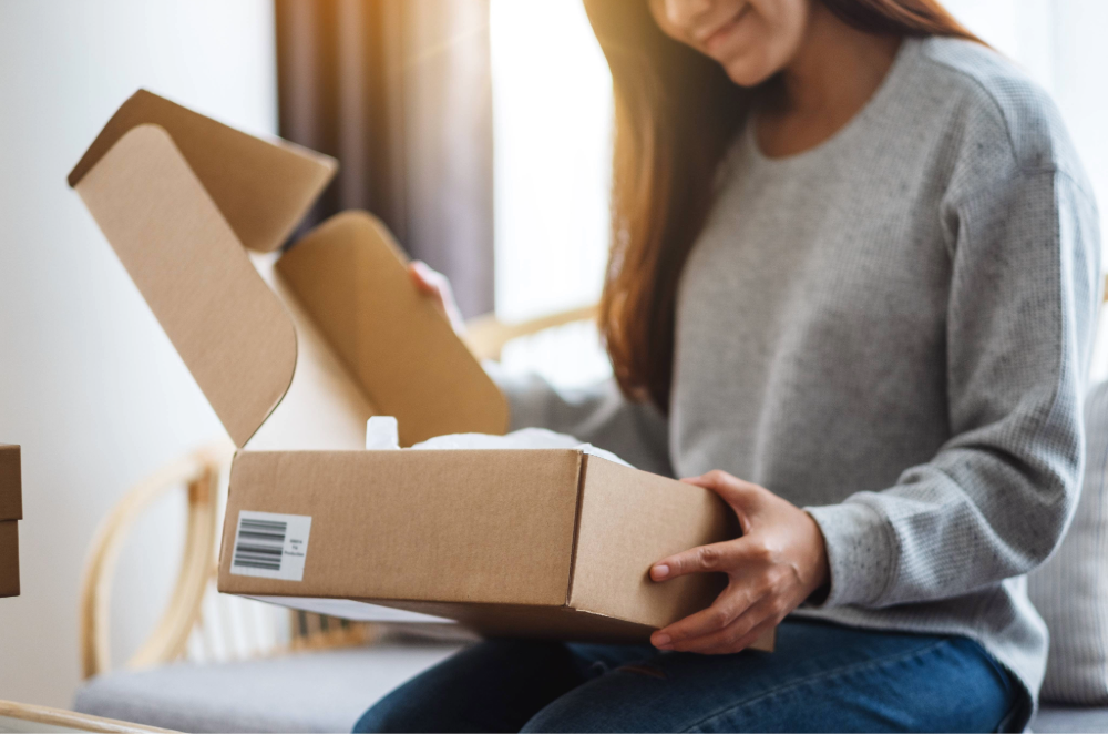 Woman opening a shipping box in living room.