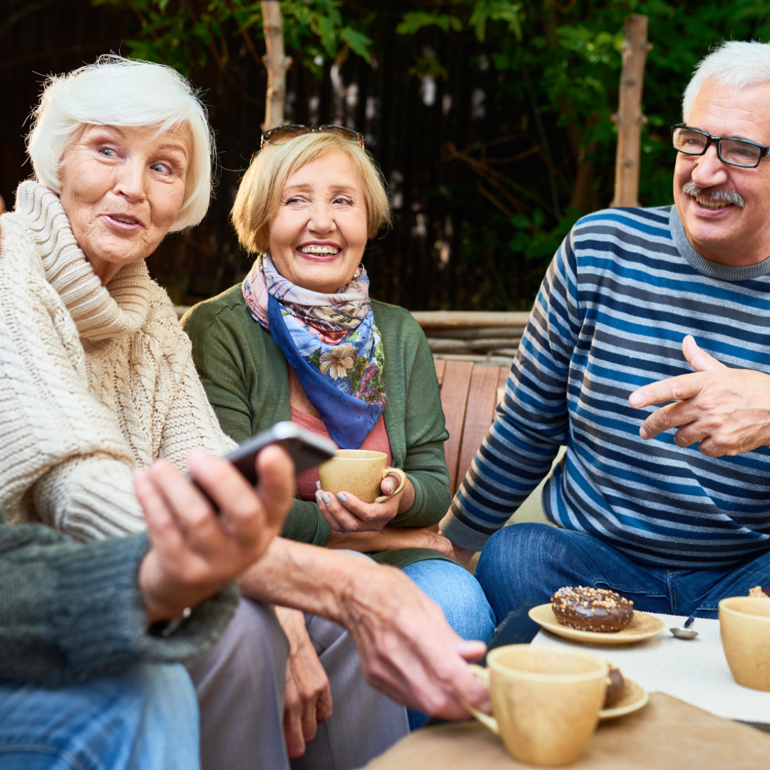 A group of three older adults talking and having coffee